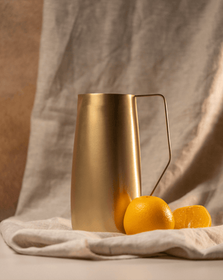 Hand-crafted brass pitcher with angled handle and lemons, perfect for entertaining, 64 oz capacity, polished shine.