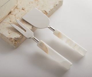 Santo alabaster cheese tools set featuring stainless steel flat knife and two-pronged fork on a cheese block.