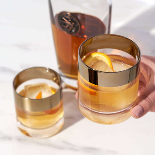 Irving™ Bronze-Rimmed Crystal Lowball Tumblers with drinks, showcasing mid-century modern design and bronze accents.
