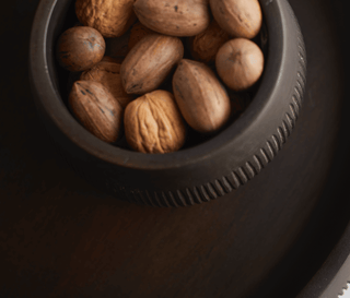 Hand-carved chiseled Leila bowl filled with mixed nuts, showcasing unique wood patterns and dark stain.