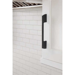 Matte black contemporary pull handle on white kitchen cabinet against subway tile backsplash.