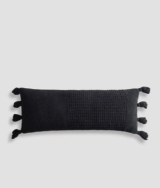Braided pom pom lumbar pillow in black with a snug removable cover and elongated memory foam design.
