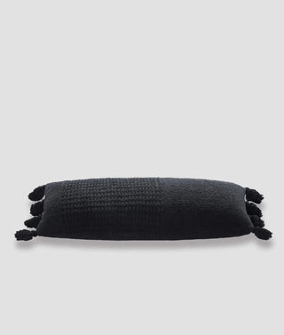 Braided pom pom lumbar pillow with a plush black cover and decorative tassels, made with memory foam and OEKO-TEX® certified.