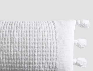 Braided Pom Pom Lumbar Pillow with textured white cover and decorative pom pom accents, made from memory foam, OEKO-TEX® certified.