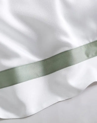 Close-up of Frame Premium Bamboo Sham Set featuring a silky white fabric with a contrasting green satin border.