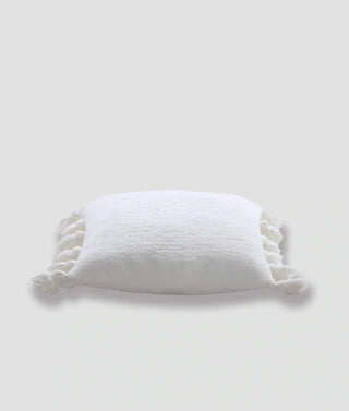 Soft white pom pom throw pillow made of memory foam with fuzzy texture and decorative pom pom edges.