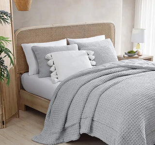 Cozy bedroom featuring a Pom Pom Throw Pillow and textured bedding in soft gray tones, offering comfort and style.