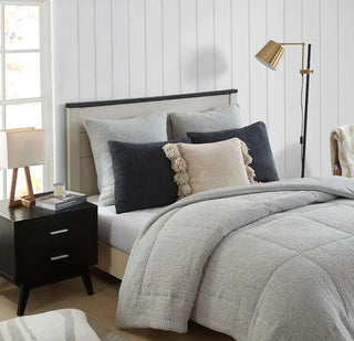 Pom Pom Throw Pillow on a cozy bed with gray bedding, surrounded by decorative pillows and a stylish lamp.