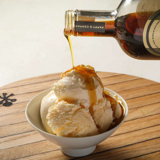 Pouring Pappy Van Winkle bourbon barrel-aged maple syrup over a bowl of vanilla ice cream.