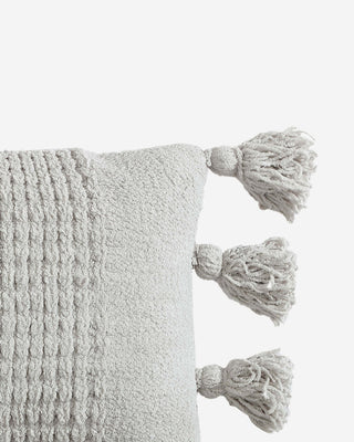 Braided pom pom lumbar pillow with textured cover and decorative tassels, made with memory foam for comfort.