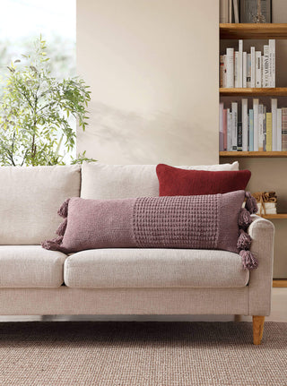 Braided pom pom lumbar pillow on cozy sofa, featuring plush texture and decorative tassels, perfect for home decor.