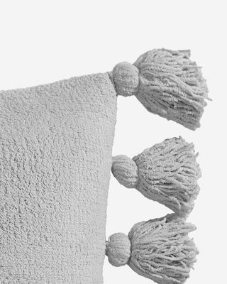 Grey pom pom throw pillow with fuzzy tassels, made of soft microfiber and memory foam for comfort.