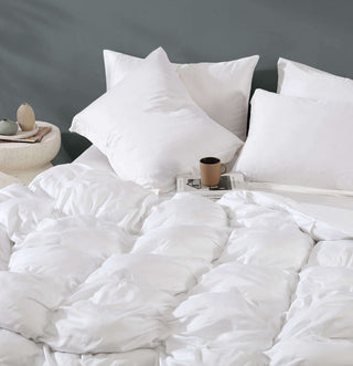 Premium Bamboo Bubble Comforter with soft white shams on a bed, stylishly arranged with pillows and a mug.