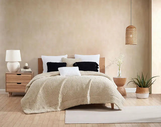 Cozy bedroom featuring a beige bedspread, fluffy pillows, and a stylish pom pom throw pillow for added decor.