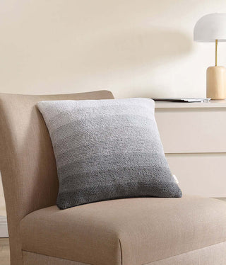 Ombre throw pillow on a beige chair, featuring a soft gradient design perfect for home decor.