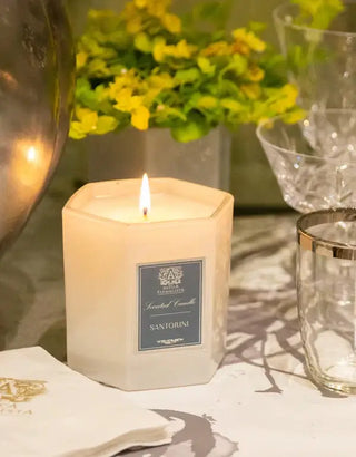 Santorini candle with a soft white hexagonal design, glowing with a warm flame, set in an elegant atmosphere.