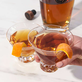 Gem crystal martini glasses with cocktails and orange peel, showcasing Venetian craftsmanship.