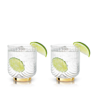 Gatsby Tumblers set of 2, polished gold and glass, perfect for elegant beverages with a lime garnish.