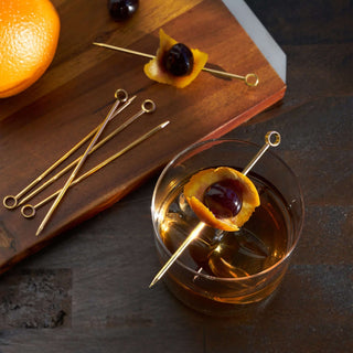 Belmont Cocktail Picks Set of 6 in polished gold with an olive and orange peel on a cocktail.
